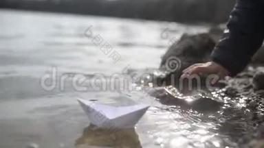 幼儿男孩在河边玩折纸船
